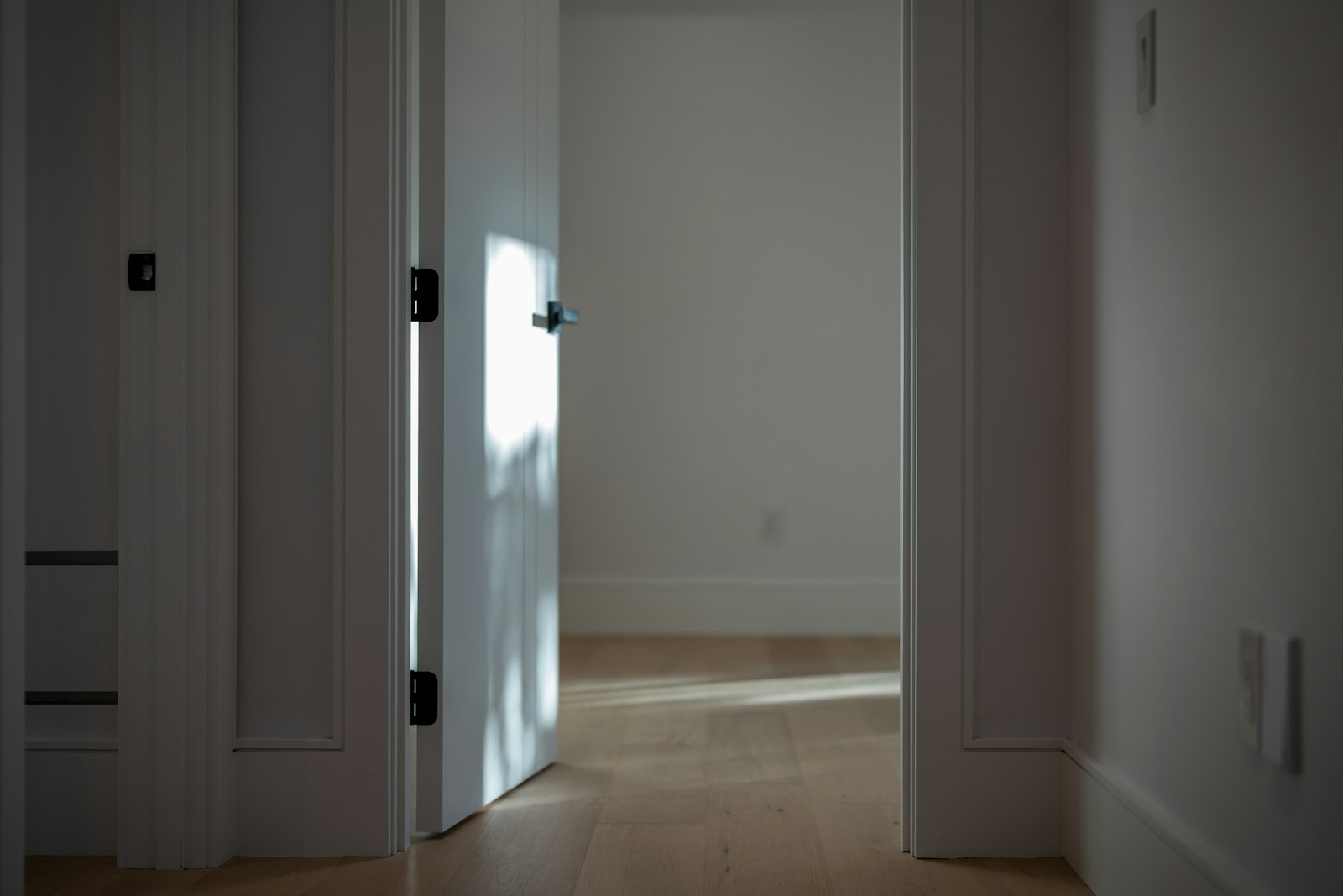 White interior door partly open onto light wood flooring