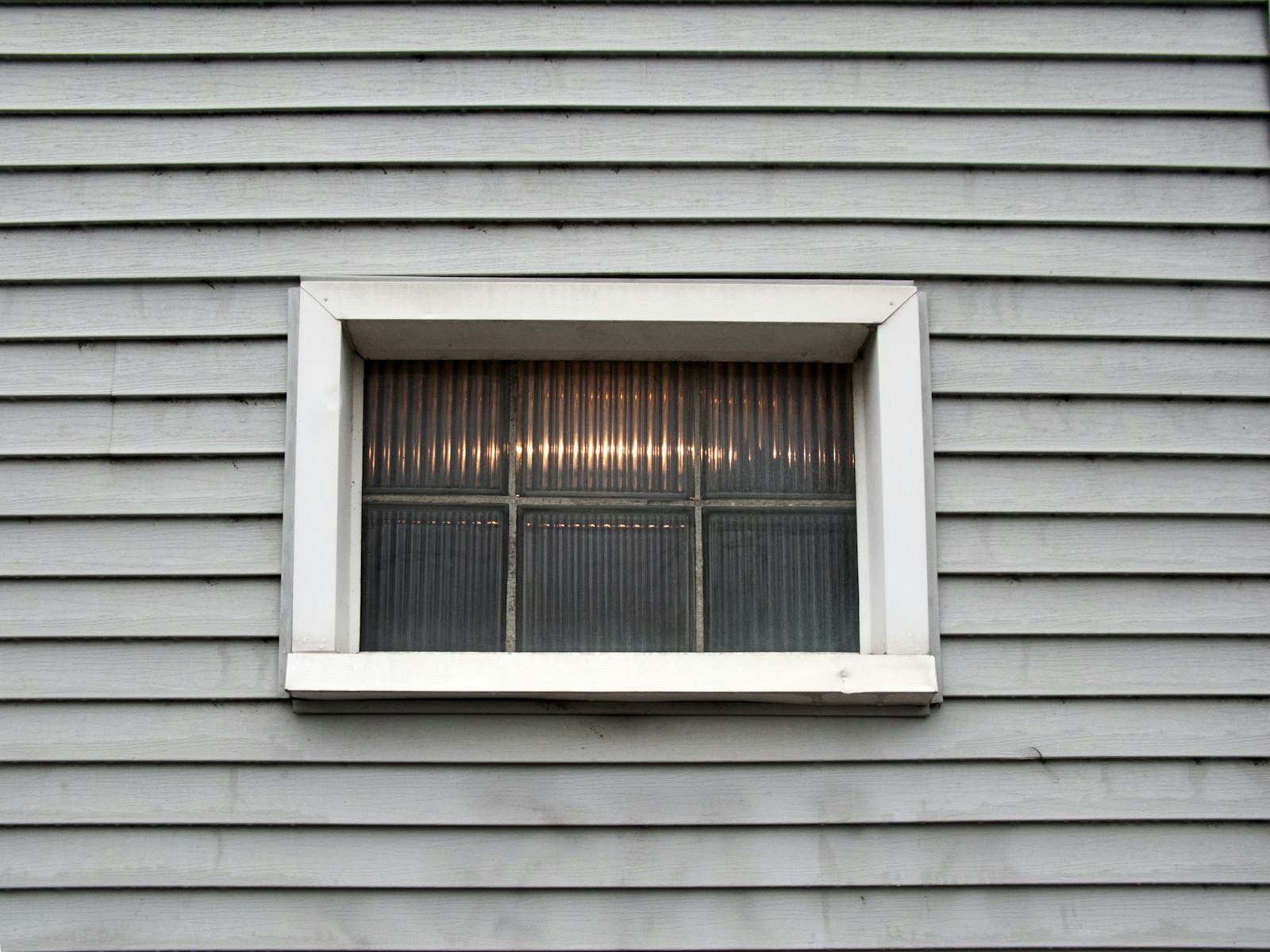 Close-up of gray horizontal lap siding around a small window